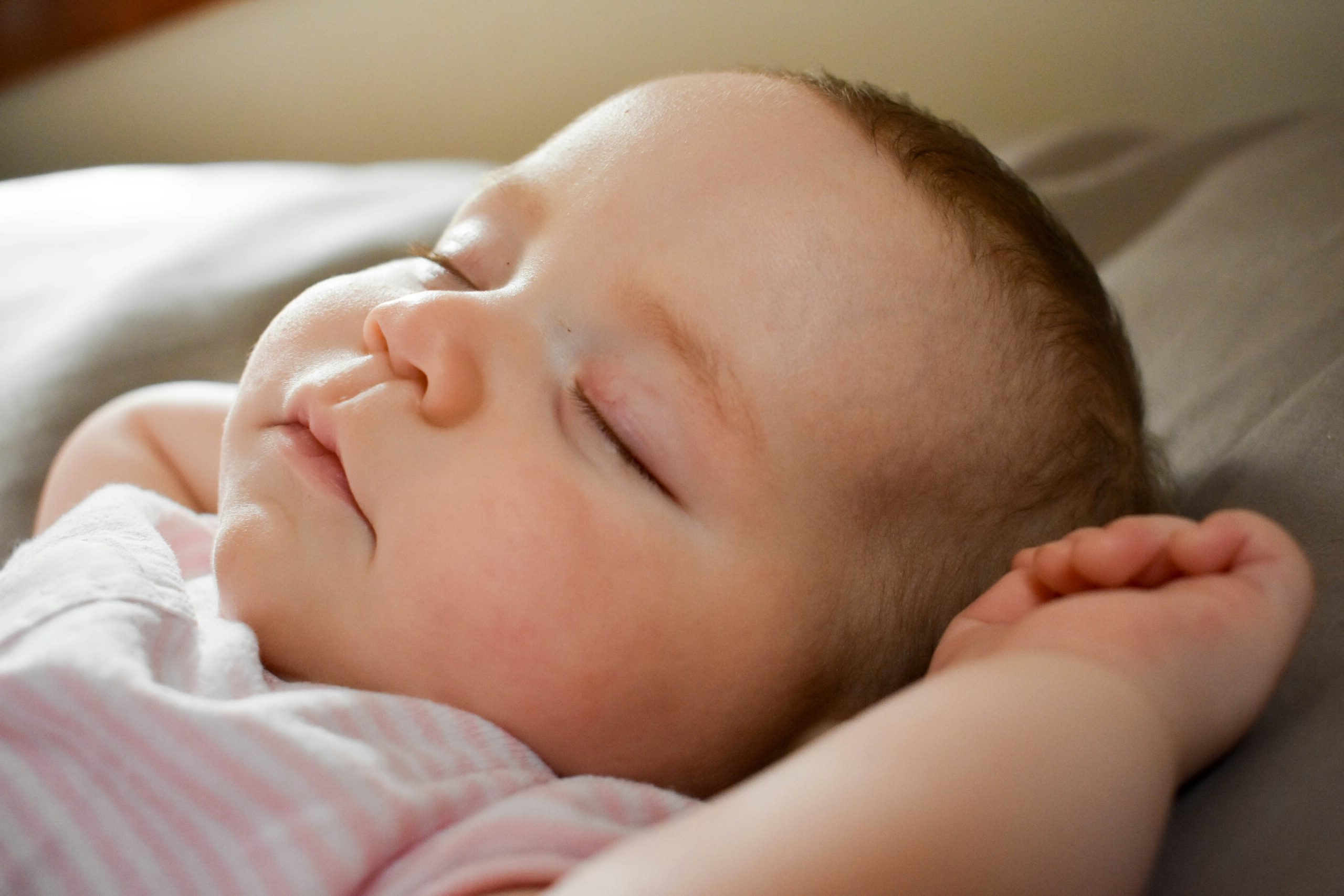 Sleeping baby resting with eyes closed on a bed